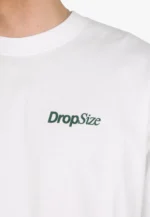 Zum Trocknen aufhängen, um Einlaufen zu vermeiden und die kastenförmige Passform zu erhalten. Bei Bedarf auf niedriger Stufe bügeln und darauf achten, nicht direkt über den Aufdruck auf der Rückseite zu bügeln.